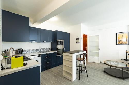 une cuisine avec des armoires bleues et une table et des chaises dans l'établissement IMMOGROOM - Rénové - Terrasse - Clim - Calme - Carnot, à Cannes
