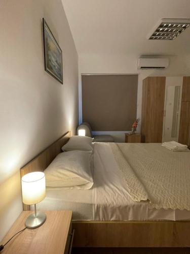 a bedroom with a bed with a lamp on a table at Apartman Dunav in Kladovo