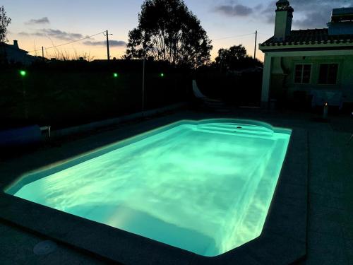 uma grande piscina num quintal à noite em Windy's Guest House em Aljezur