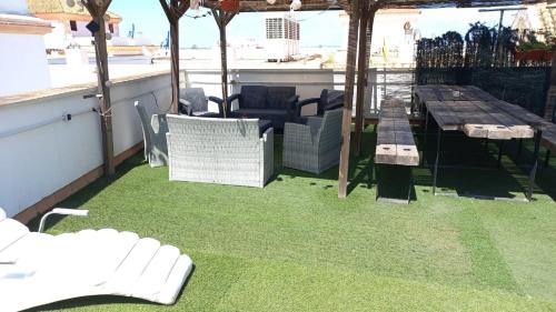 a patio with green grass and a table and chairs at Casa al Compas De ROSARIO by Cadiz4Rentals in Cádiz