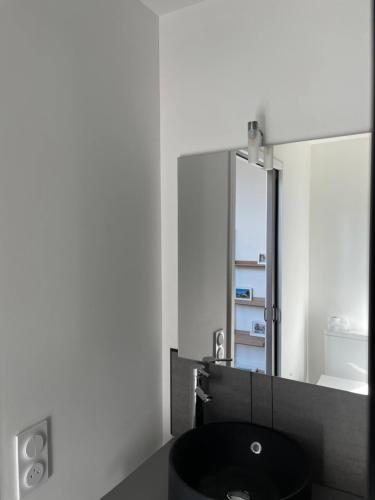 une salle de bain avec un lavabo noir et un miroir dans l'établissement Charmant Studio proche Centre Ville et Gare, à Lourdes