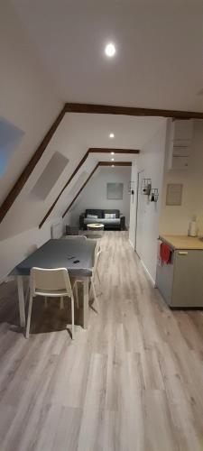 Cette chambre mansardée comprend une table et un canapé. dans l'établissement Appartement dans maison de 1789 au centre de Vitré, à Vitré