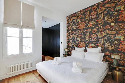 - une chambre avec un grand lit blanc et du papier peint dans l'établissement Pick A Flat's Apartment in Montorgueil - Rue Saint Joseph, à Paris