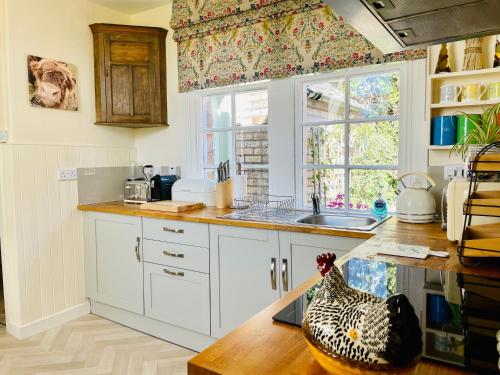 a kitchen with white cabinets and a chicken sitting on a counter at Carnell Country Estate & Holiday Cottages in Ayrshire in Hurlford