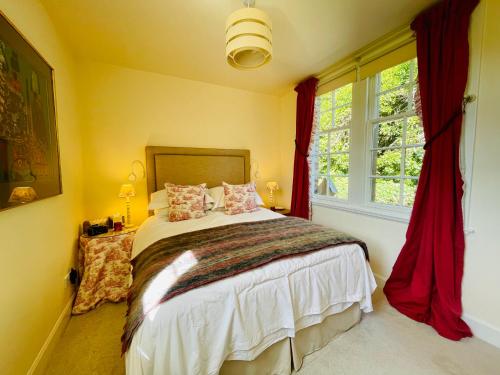 a bedroom with a bed with red curtains and a window at Carnell Country Estate in Hurlford
