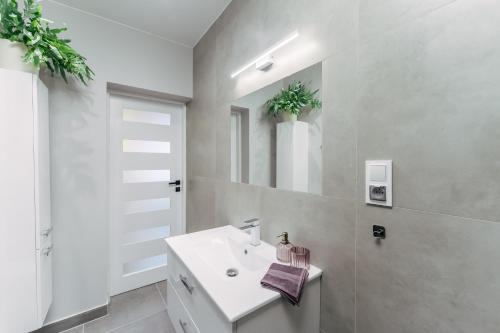 a white bathroom with a sink and a mirror at Apartamenty Greenpoint Dźwirzyno in Dźwirzyno