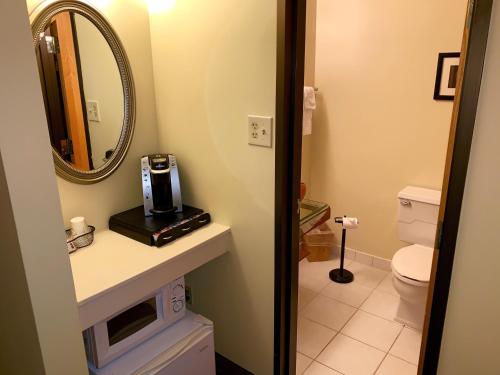 a bathroom with a sink and a toilet and a mirror at The Academy Hotel Colorado Springs in Colorado Springs