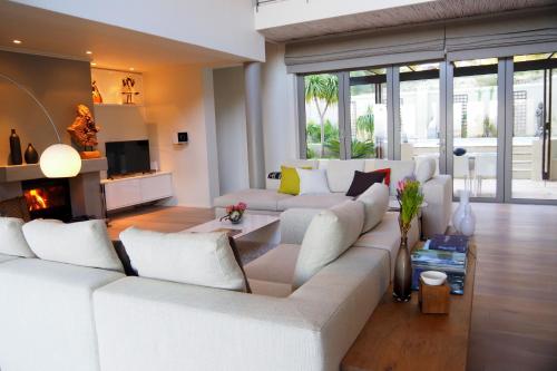 a living room with a white couch and a fireplace at Pure Guest House in Hout Bay