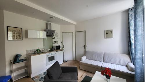 un salon avec un canapé et une cuisine dans l'établissement Charmant 2 pièces avec terrasse proche centre ville - Parking Gratuit à proximité, à Lourdes