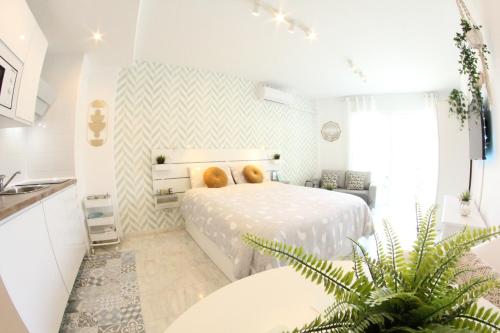 Un dormitorio blanco con una cama y una planta en TORREMOLINOS - NEW CENTRAL STUDIO PLATA WITH BALCONY, en Torremolinos