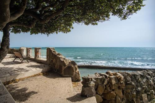 a rock wall next to the ocean with a bench at Villa MG Hotel in Santa Marinella