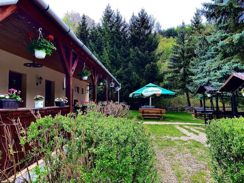 patio z parasolem, stołem i ławkami w obiekcie Fakanalas Fogadó w mieście Pásztó