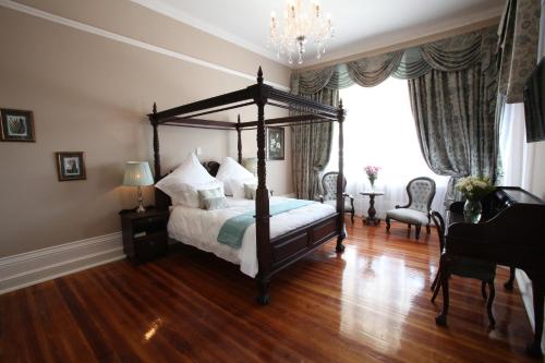 a bedroom with a canopy bed and wooden floors at Park Place Boutique Guesthouse in East London