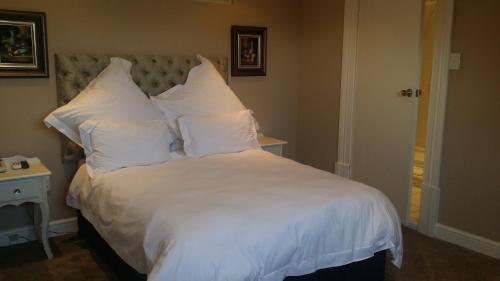 a large bed with white sheets and pillows at Park Place Boutique Guesthouse in East London
