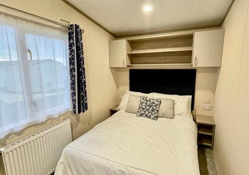 a small bed in a small room with a window at Luxury 3 bedroom caravan between Perranporth and Newquay, Cornwall in Newquay