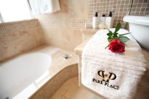 a bathroom with a towel with a red rose on it at Park Place Boutique Guesthouse in East London