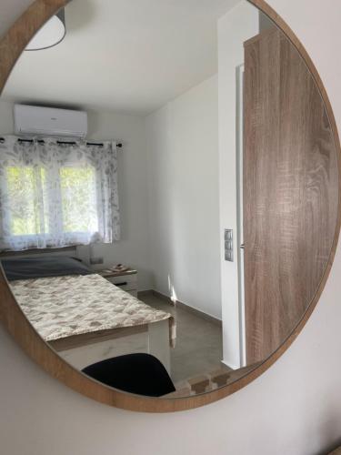 a mirror in a room with a bed and a table at M & F HOUSE (παραλία Μαρκοπούλου Ωρωπού) in Oropós