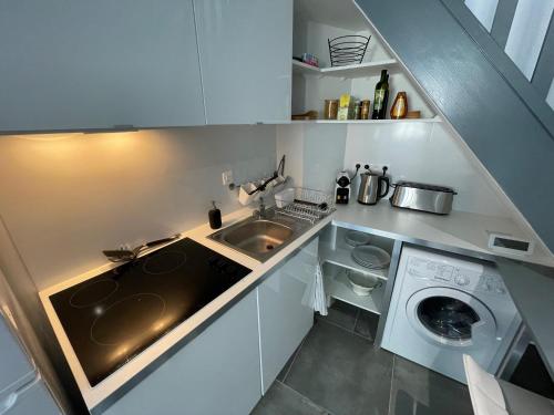 a small kitchen with a sink and a washing machine at Jolie duplex central climatisé in Vernon