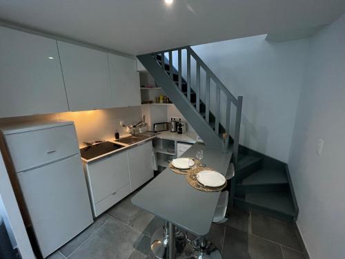 a kitchen with white cabinets and a staircase at Jolie duplex central climatisé in Vernon