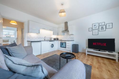 a living room with a couch and a tv at Stansted Airport & Bishops Stortford Town Centre Professional Apartment in Bishops Stortford