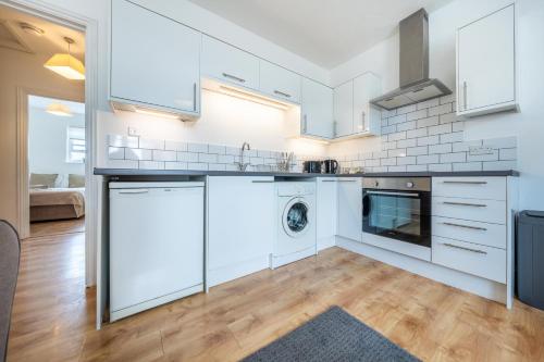 a kitchen with white cabinets and a washer and dryer at Comfortable 2 Bed Apartment Near Stansted Airport & Bishops Stortford in Bishops Stortford