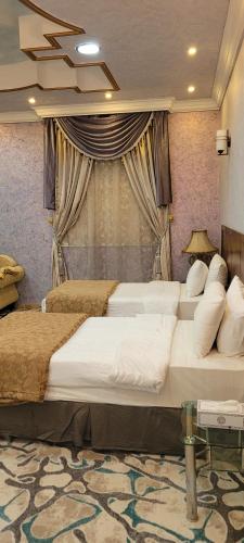 a bedroom with three beds in front of a window at سويت ان العلا للشقق المفروشة الخاصة Sweet In alula Apartments and organizing tours in Al-ʿUla
