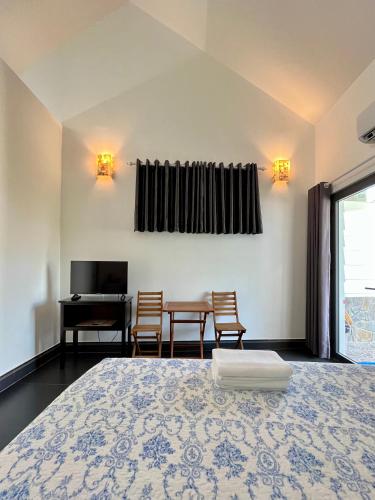 a bedroom with a bed and a table and chairs at Catsen Bungalows & Pool Phan Thiet in Phan Thiet