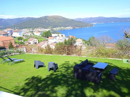 un cortile verde con tavoli e sedie e vista sull'acqua di MIRAFLORES Alojamiento Turístico a Muros