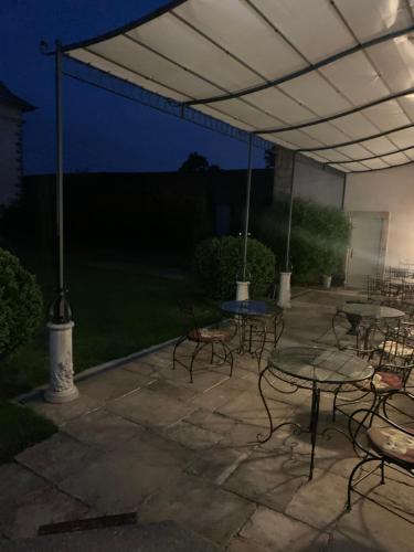 a patio with tables and chairs under a canopy at night at Le Château de Failloux, Piscine intérieure in Épinal