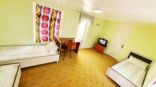 a room with two beds and a table and a window at Soliha&Yulduz Guesthouse in Bukhara