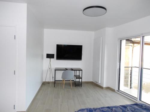 Dieses weiße Zimmer verfügt über einen Tisch und einen TV an der Wand. in der Unterkunft La Ferme des Cerisiers in Reventin-Vaugris