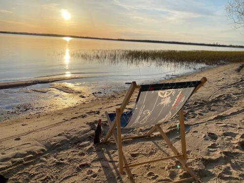 a chair sitting on a sandy beach next to the water at Marina Lubkowo Dom Czarna Perła in Lubkowo
