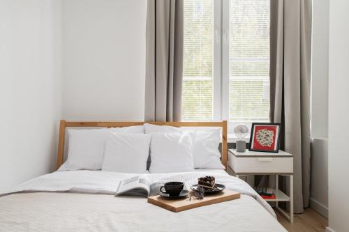 Un dormitorio con una cama con una bandeja de comida. en oompH Warsaw Nowy Swiat Apartment, en Varsovia