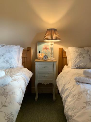 a bedroom with two beds and a table with a lamp at Hawthorn Cottage at Waingrove Farm in Fulstow