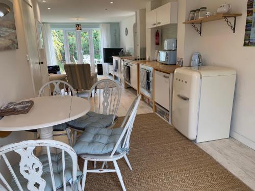 a kitchen with a table and chairs and a refrigerator at Little Karenza is the perfect Cornish getaway in Saint Anthony