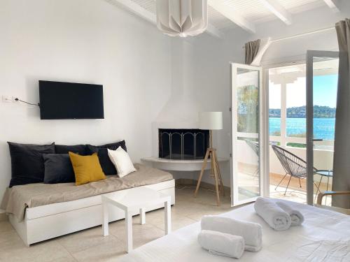 uma sala de estar branca com um sofá e uma televisão em Palm Suite Yellow em Porto Heli