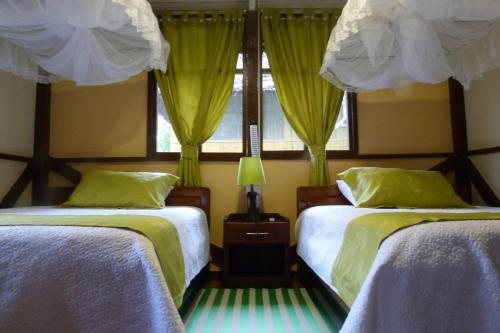 a bedroom with two beds with yellow curtains and a window at Yarina Eco Lodge in Derna