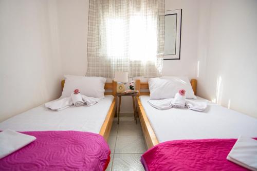 two twin beds in a small room with pink sheets at Myloi Loggou in Sykia Chalkidikis