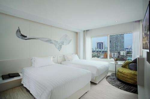 a hotel room with two beds and a window at Centara Watergate Pavilion Hotel Bangkok in Bangkok