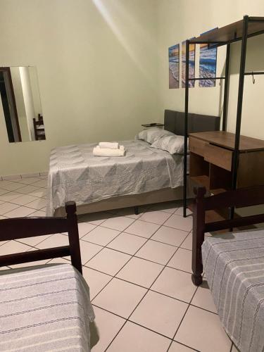 a room with two beds and a table and a mirror at Pousada Meraki Beach in Caraguatatuba