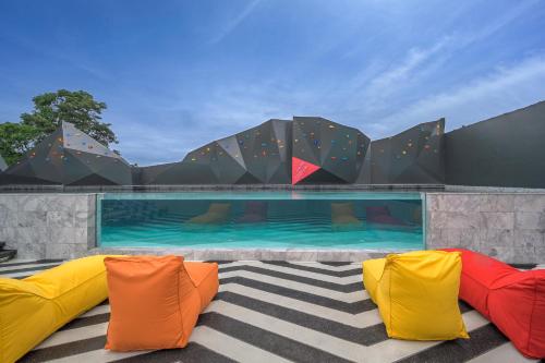 a swimming pool with colorful cushions in front of a building at COSI Krabi Ao Nang Beach - SHA Plus in Ao Nang Beach