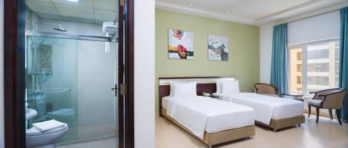 two beds in a room with a shower and a bathroom at Centara Life Muscat Dunes Hotel in Muscat