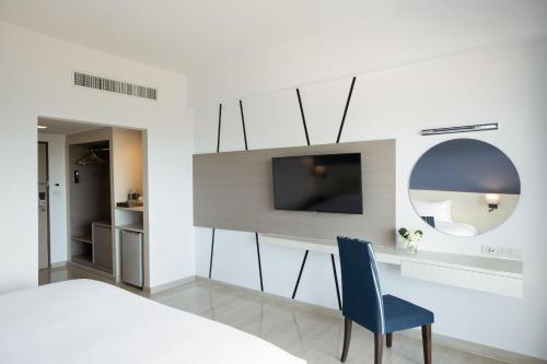 a bedroom with a bed and a tv and a blue chair at Centara Life Cha-Am Beach Resort Hua Hin in Cha Am