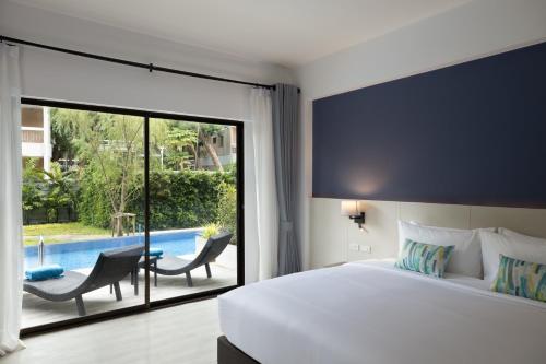 a bedroom with a bed and a sliding glass door to a pool at Centara Life Cha-Am Beach Resort Hua Hin in Cha Am