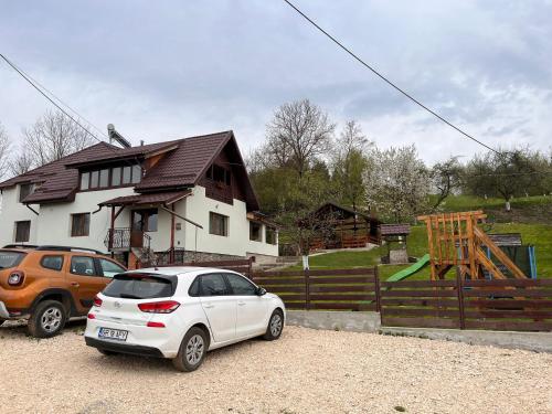 a white car parked in front of a house at Pensiunea Poiana Luminoasă in Bughea de Jos