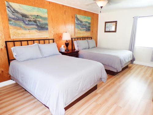 two beds in a room with wood paneling at Shoreline Cottages in Fort Bragg