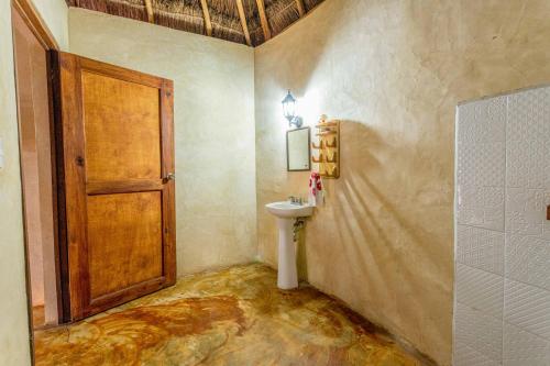 a bathroom with a sink and a wooden door at Cabañas Santa Cruz Homún in Homún