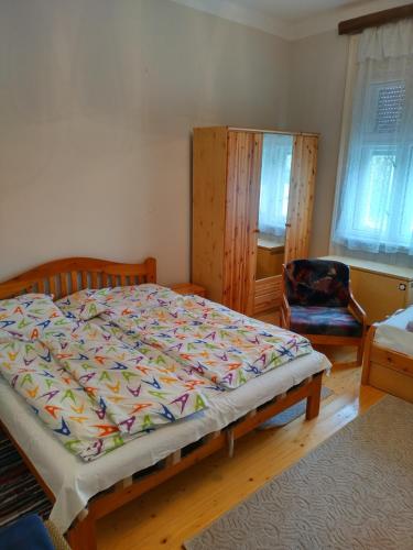 a bedroom with a large bed and a chair at 8513 Mihályháza - Rózsi Vendégház in Mihályháza