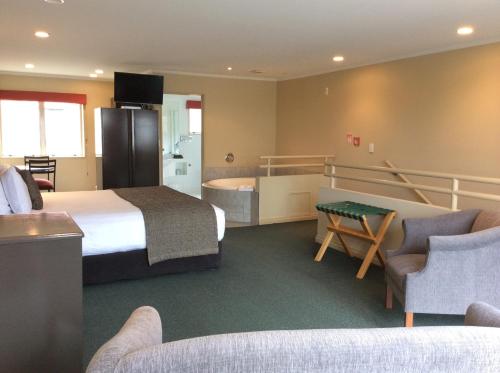 a hotel room with a large bed and a bathroom at Cornwall Motor Lodge in Palmerston North
