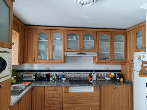 a kitchen with wooden cabinets and granite counter tops at Comparte Espacio en Chiclana in Chiclana de la Frontera